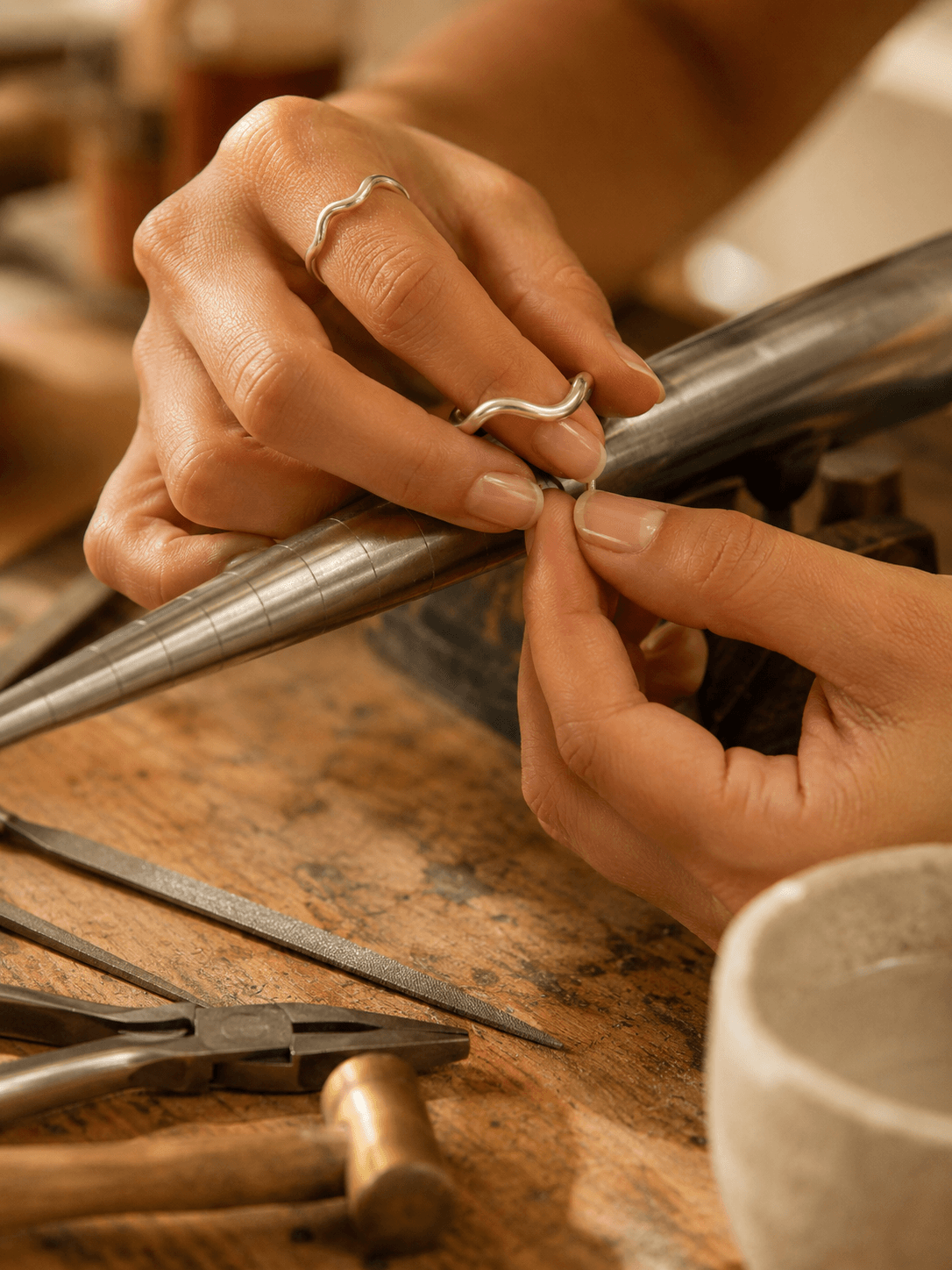 Manos dando forma a una pieza de plata en el taller